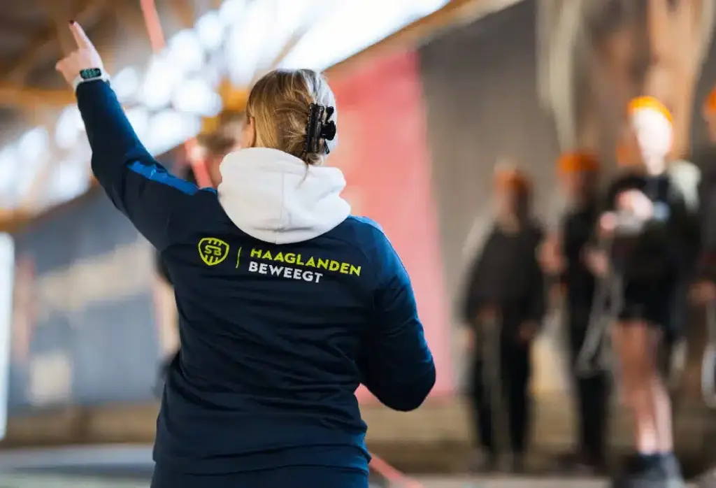 Buurtsportcoach die iets aanwijst aan deelnemers van haar les