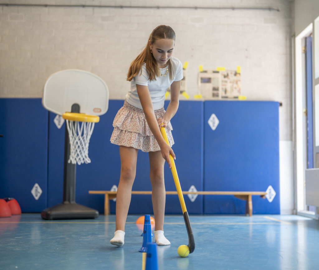 Meisje dat hockeyt in de gymzaal